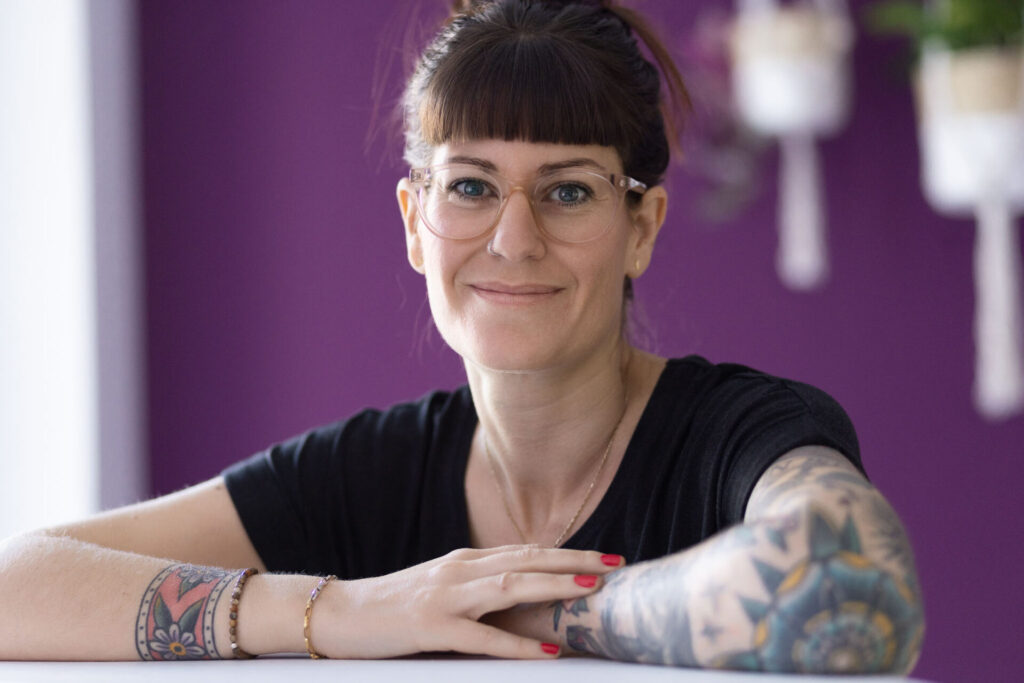Laura Köppen, die Gründerin des Place to Be, blickt lächelnd mit verschränkten Armen in die Kamera.